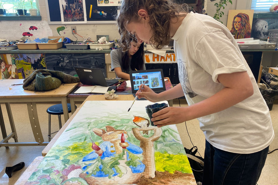 Senior Winnie Kenney paints her ceiling tile with the cover of Peter Rabbit