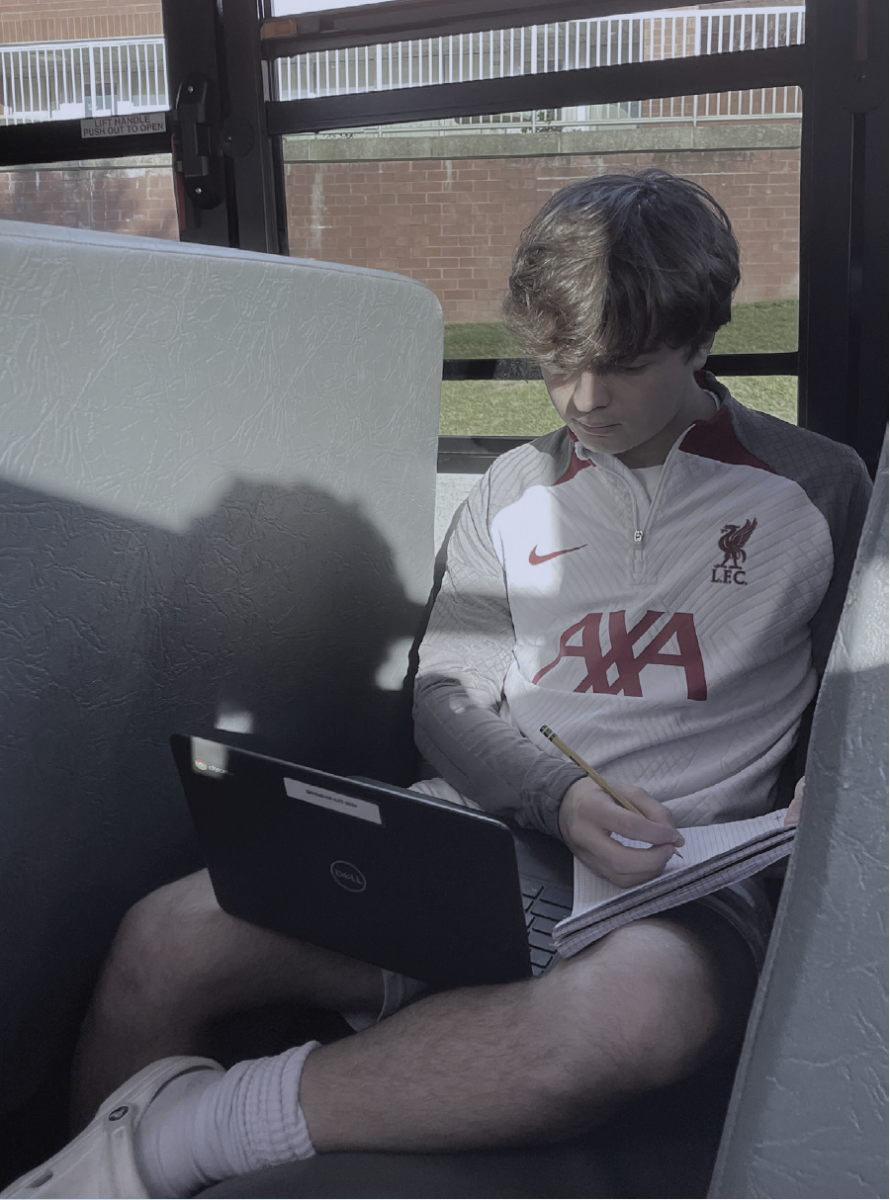 On+the+bus+to+an+away+soccer+game%2C+senior+Fritz+Navickas+tries+his+best+to+focus+on+the+loud+bus+to+get+some+of+his+homework+done.
