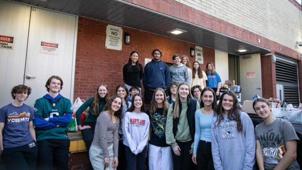 A COLLECTION OF CANS • Haven Helps members stand in front of the cans raised by the school after hauling them outside.
