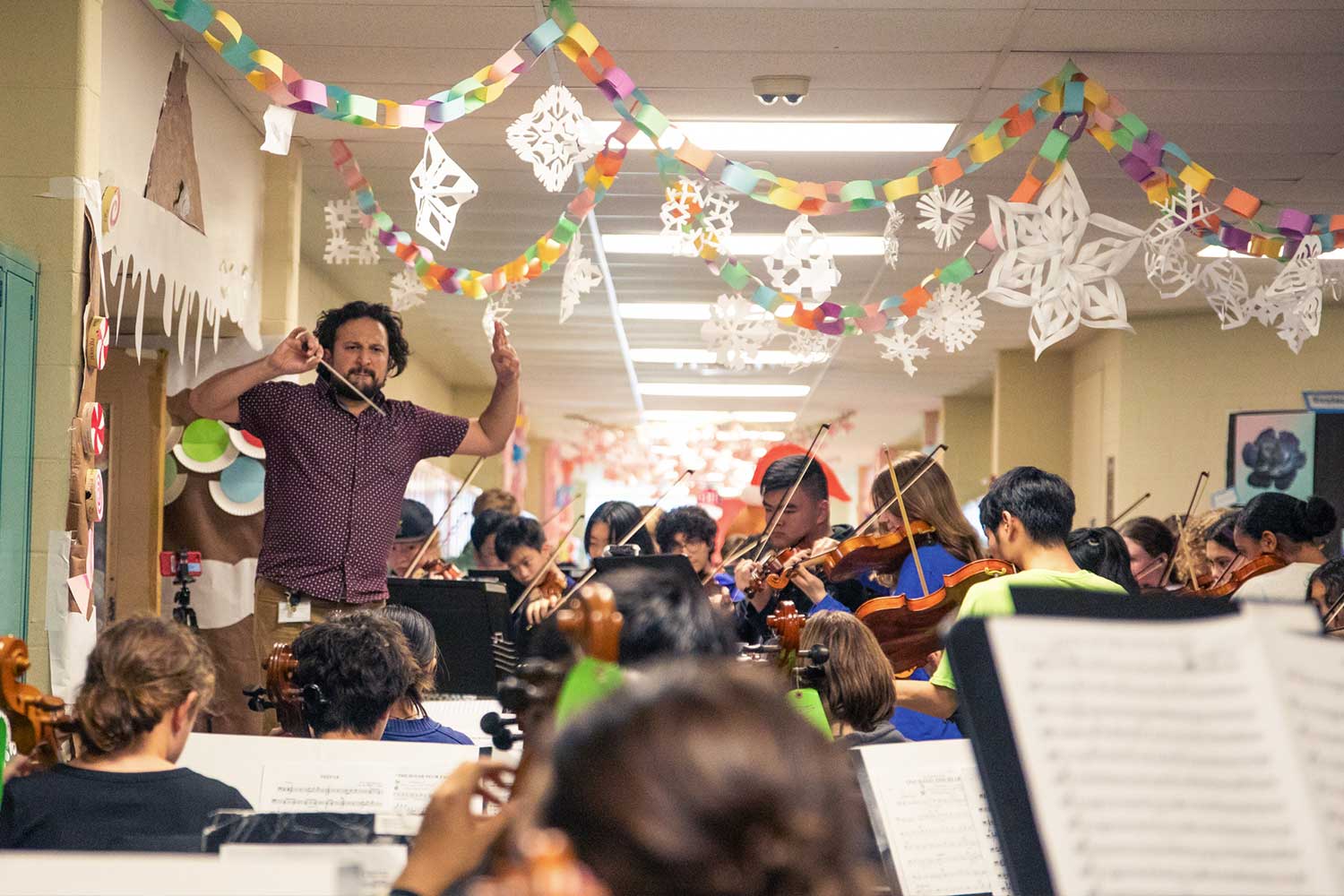 Music teacher Mr. Nick Pignataro conducts the symphony orchestra through ‘The Nutcracker’ on the holiday-themed second floor hallway of Strath Haven High School on Monday, December 11, 2023.