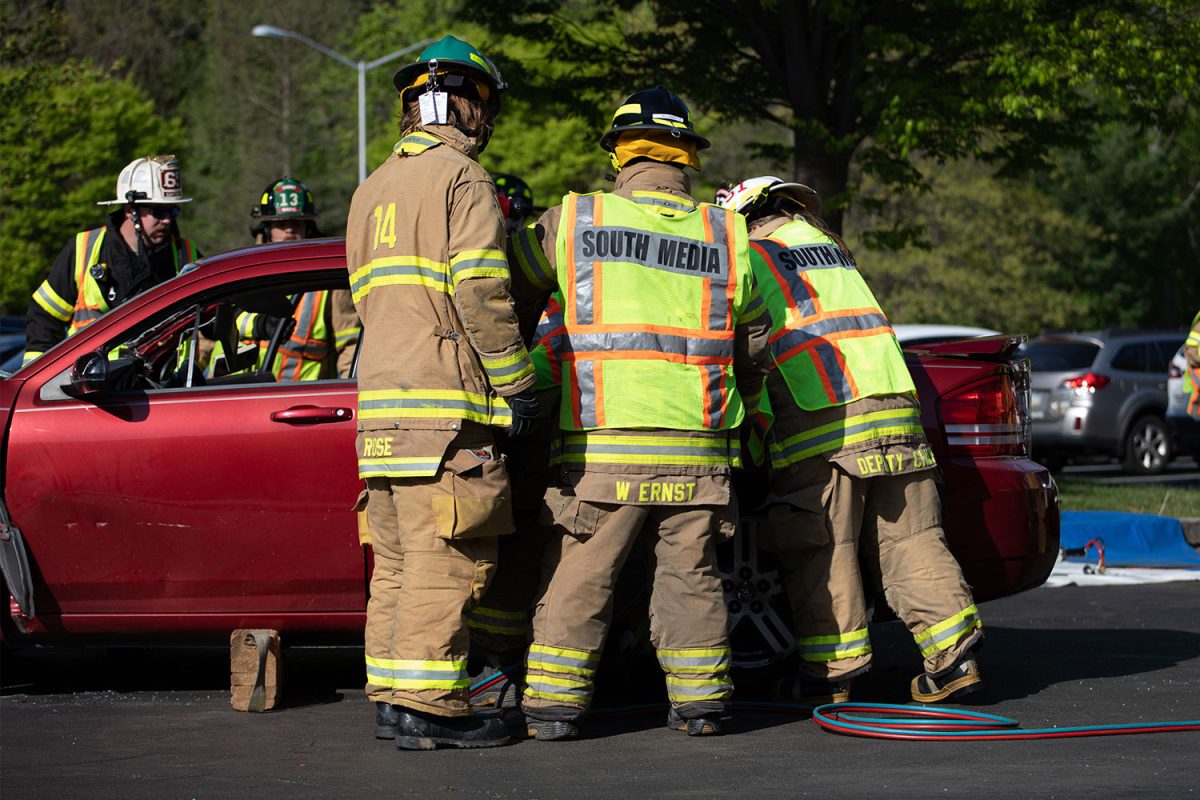 Volunteers from the South Media Fire Department gather around the car used in the 2023 mock crash.