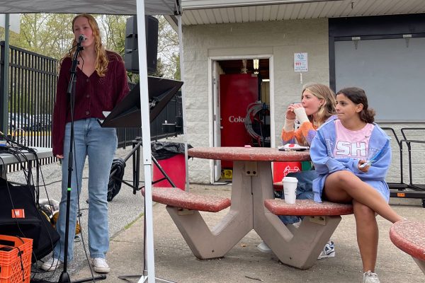 Senior Callie Susek sings from underneath a tent that kept performers dry during the on-and-off showers during Spring Fling.