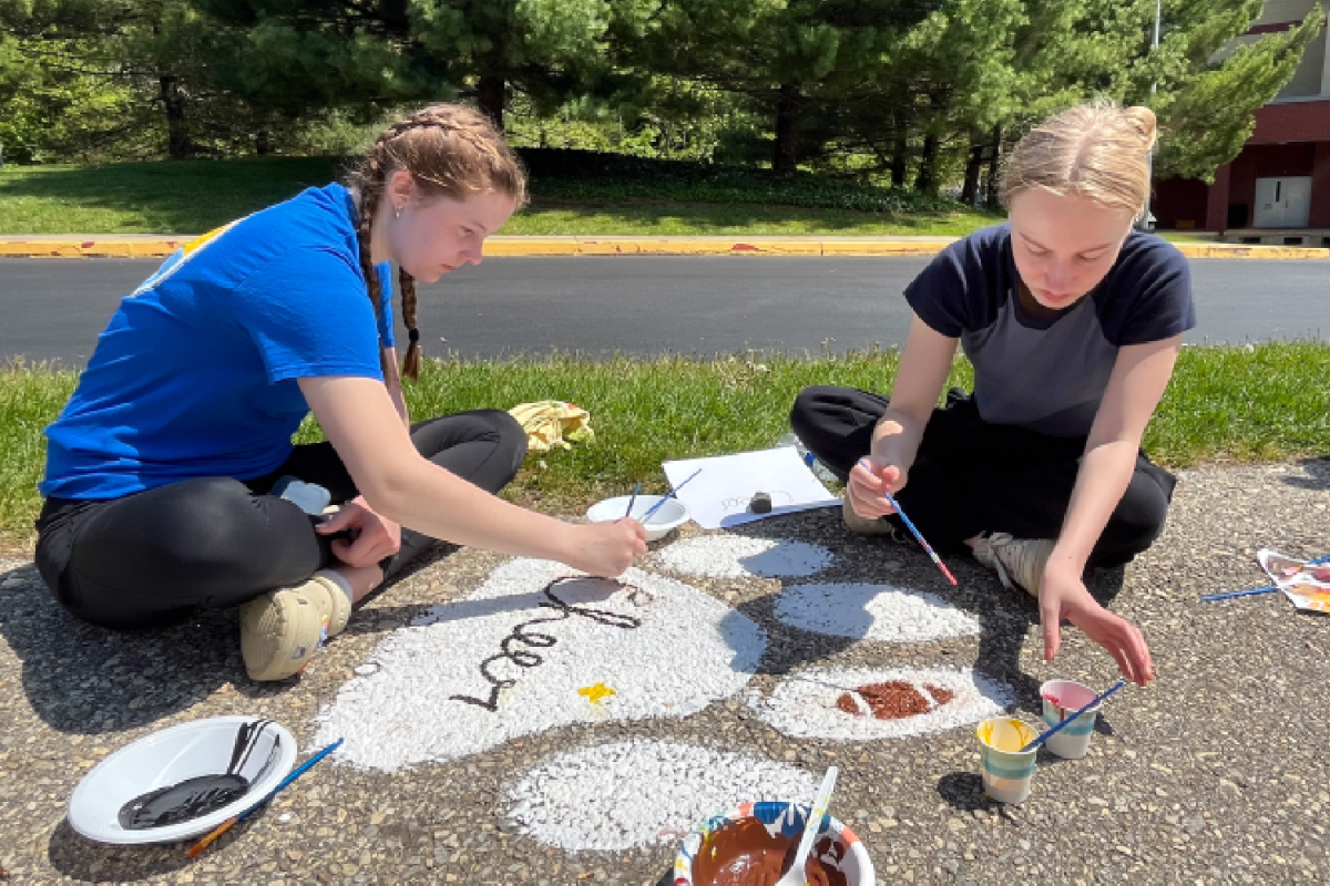 Sophomores Julia Smirnova and Audrey Sill paint the Haven Cheer paw print on April 28.