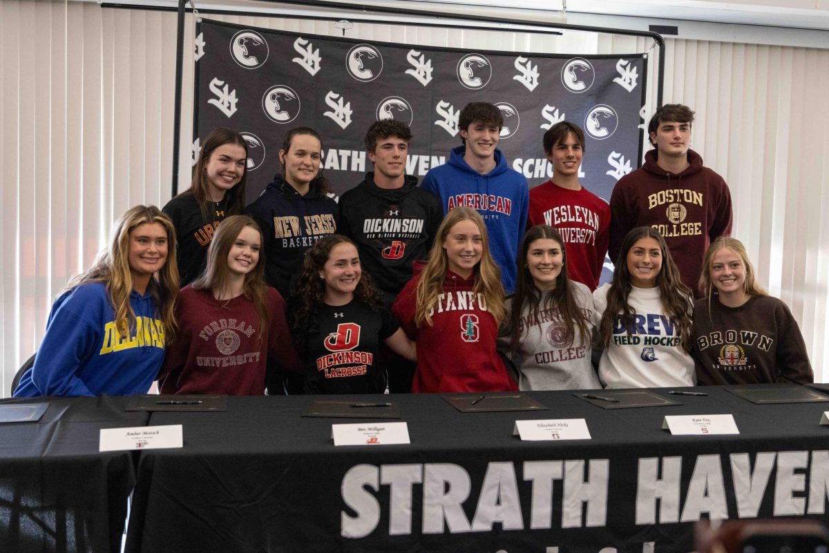 Twelve student-athletes pose for a group photo during the fall athletic signing ceremony in the library on Nov. 13.