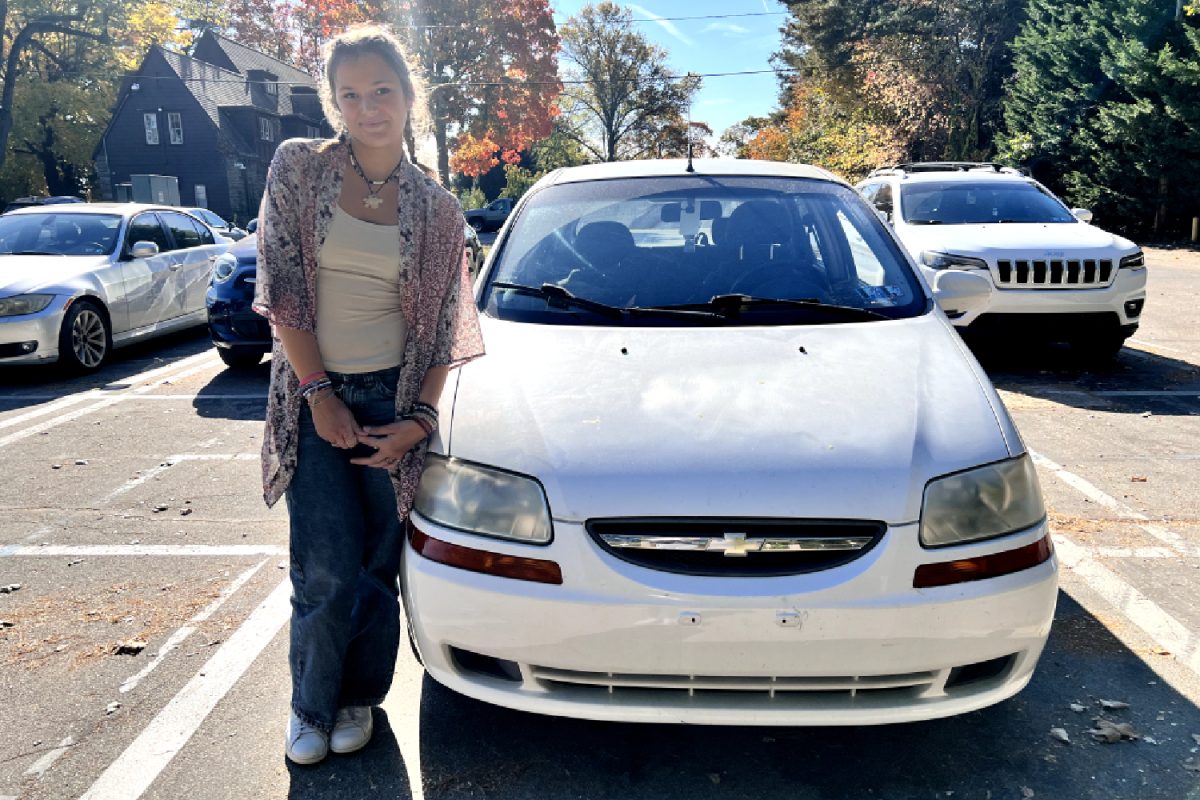 Senior Paige Katsapis poses with her white Chevy Aveo in the Ortho lot. 