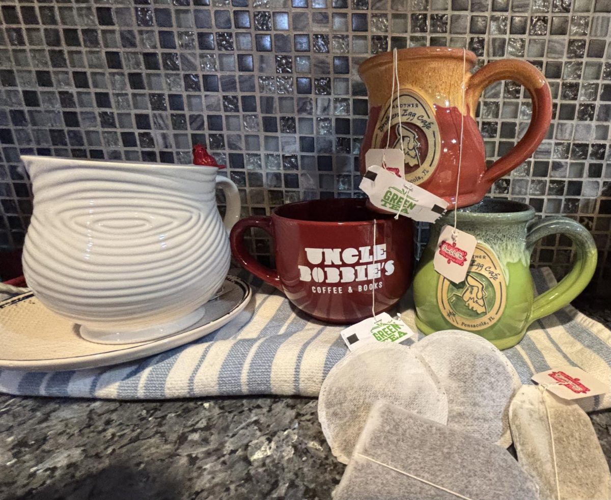 Three tea bags and cups sit on a kitchen counter.