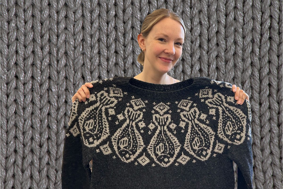 Ms. Sarah Holt proudly poses with an intricate fish motif sweater that she knitted. 