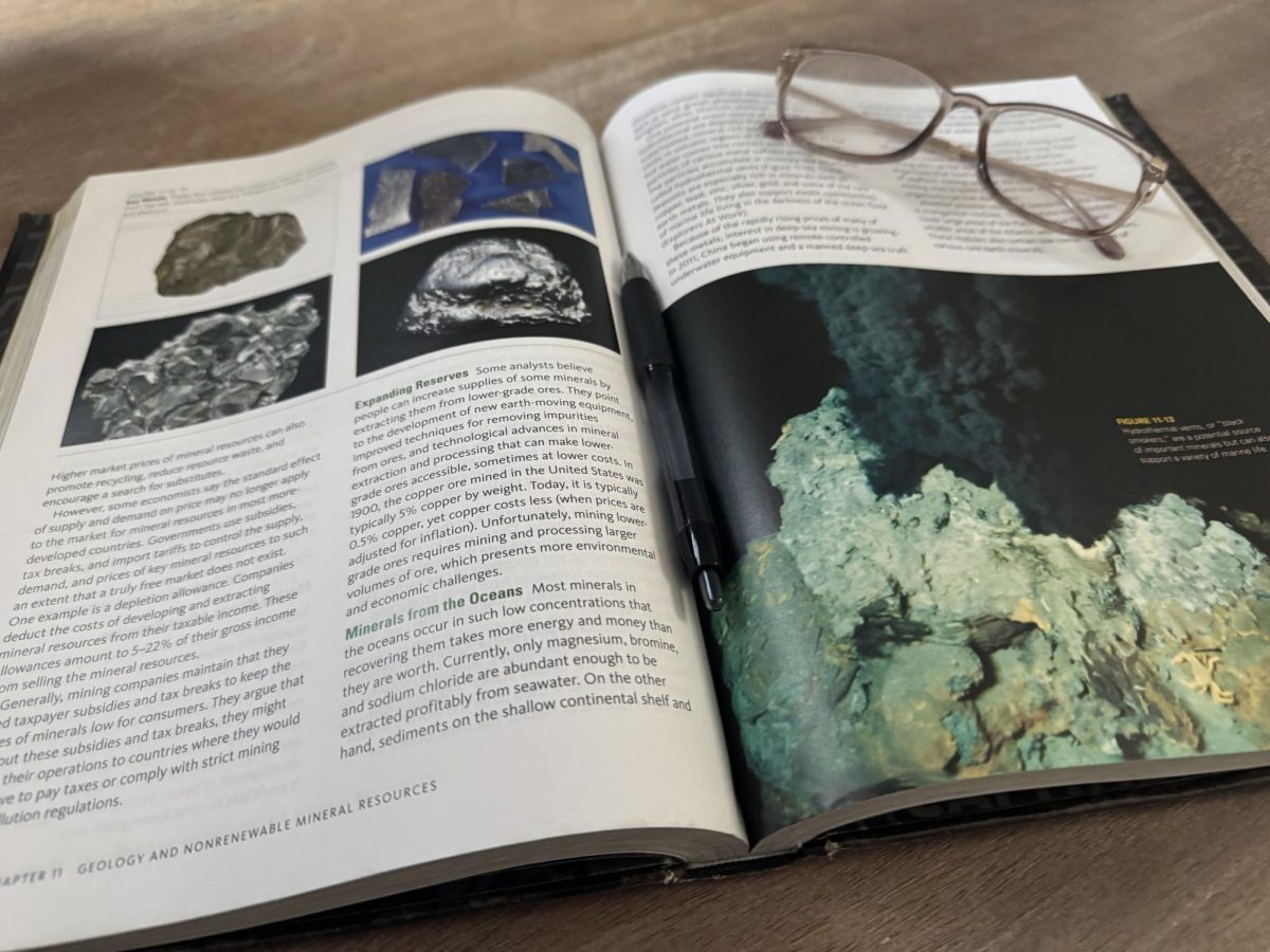 STUDY SCENE • Environmental Science textbook sits open with glasses and a pen. 