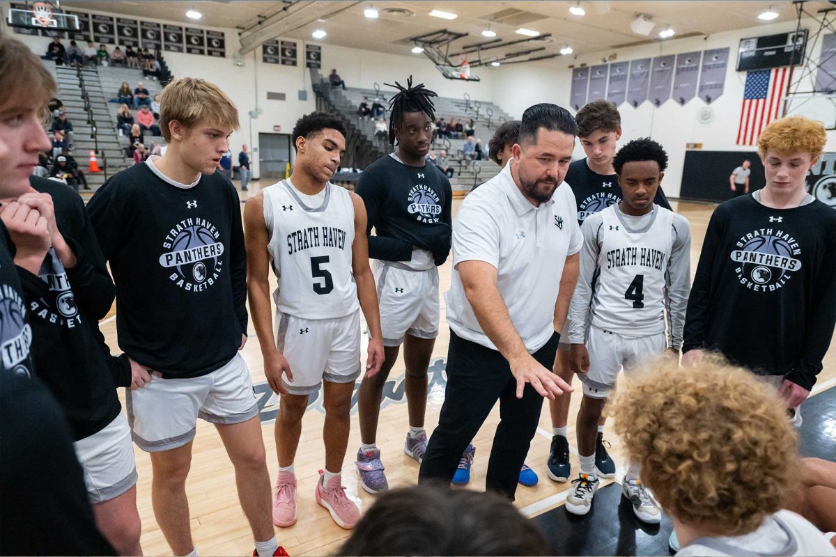 Head boys varsity basketball coach Tim Livingstone chats with the team during a timeout at the game against Plumstead Christian on Thursday, December 12. The Strath Haven Panthers won against the PCS Panthers with a final score of 67-32.