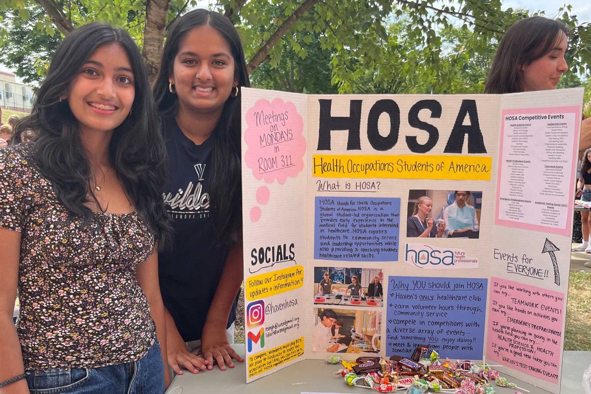 HOSA leaders Lavanya Dixit and Rheya Singh greet students at the activities fair with a smile. The co-presidents gave out candy and explained what the new club is all about.