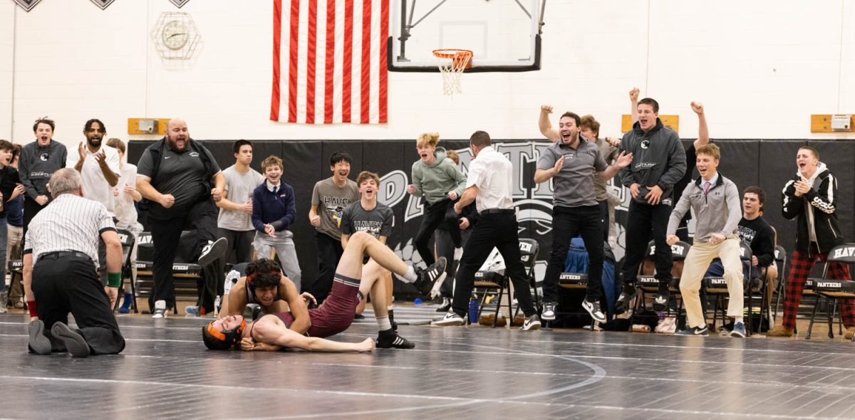 Sophomore Aromal Rajesh's teammates and coaches jump up and down in excitement as he finally pins down his opponent. 