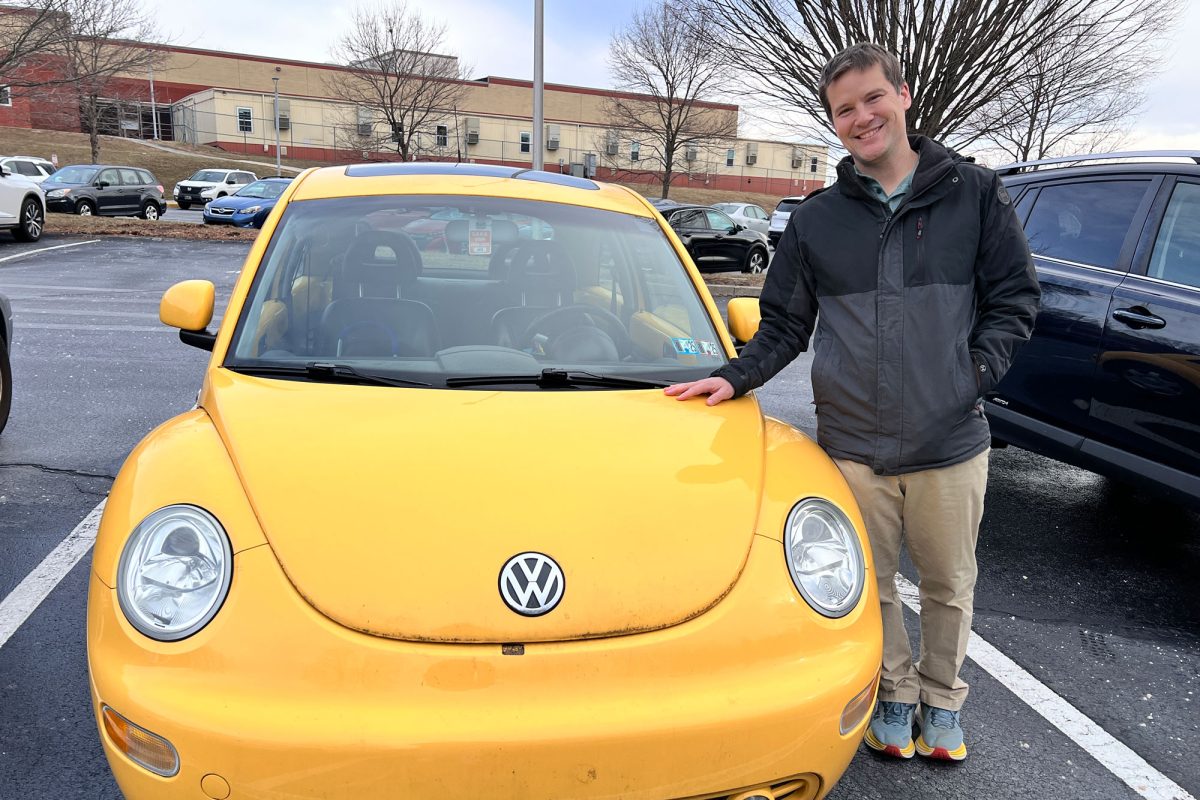 Mr. Peterson stands with a smile beside his 2000 Volkswagen Beetle. 