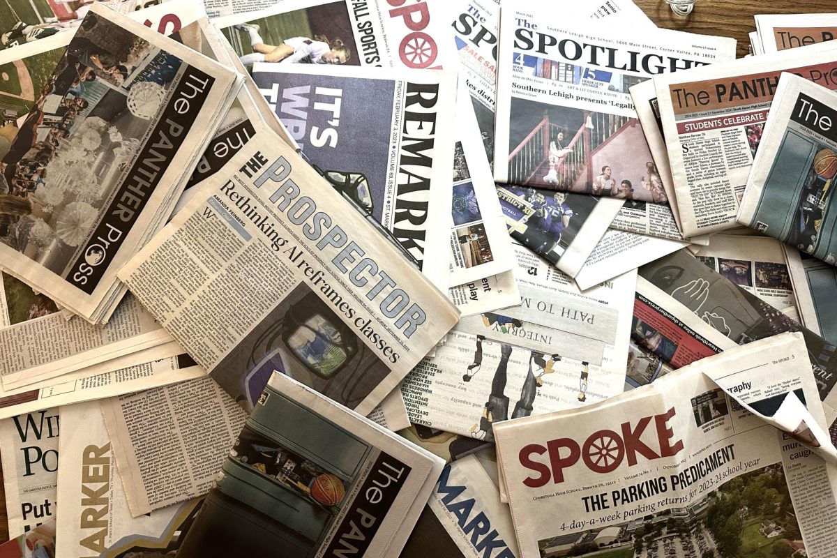 A plethora of student news publications lay scattered across s a table.
