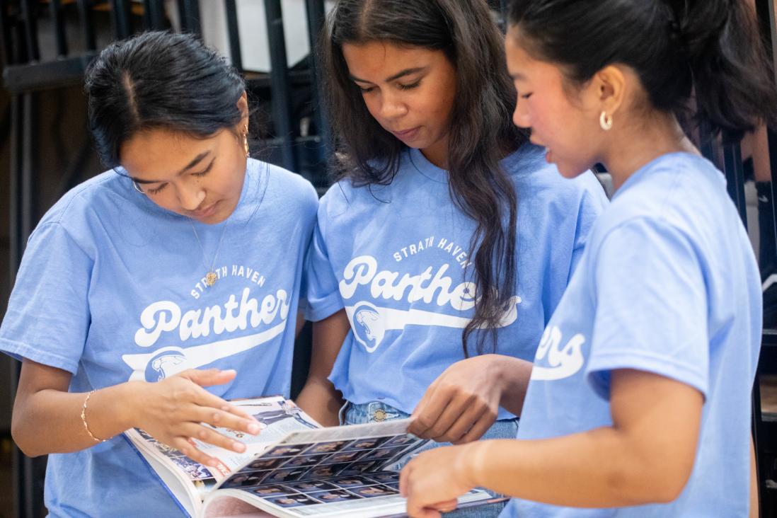 Daksha Nair (12), Maya Putty (12), and Minori Saito (12) point out a familiar face in the yearbook. Seniors were able to receive their yearbooks first, giving them plenty of time to admire the new yearbooks.
