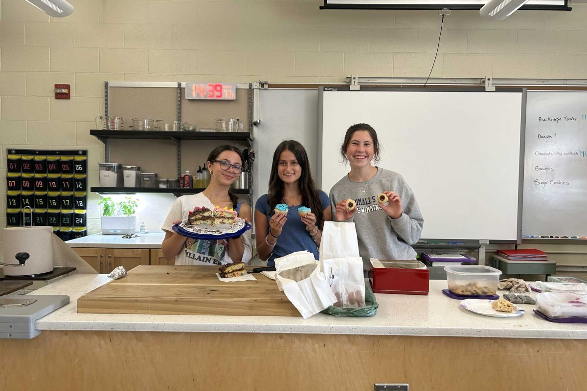Foodie Friends club presidents Roxanna Shelton, Sabine Fried, and Kaylin Fava hold up treats at the first meeting for the club on Monday, September 15. The meeting, which was in the cooking room, served as an introduction to the club as the presidents discussed goals for the year as everyone enjoyed student-baked treats. 