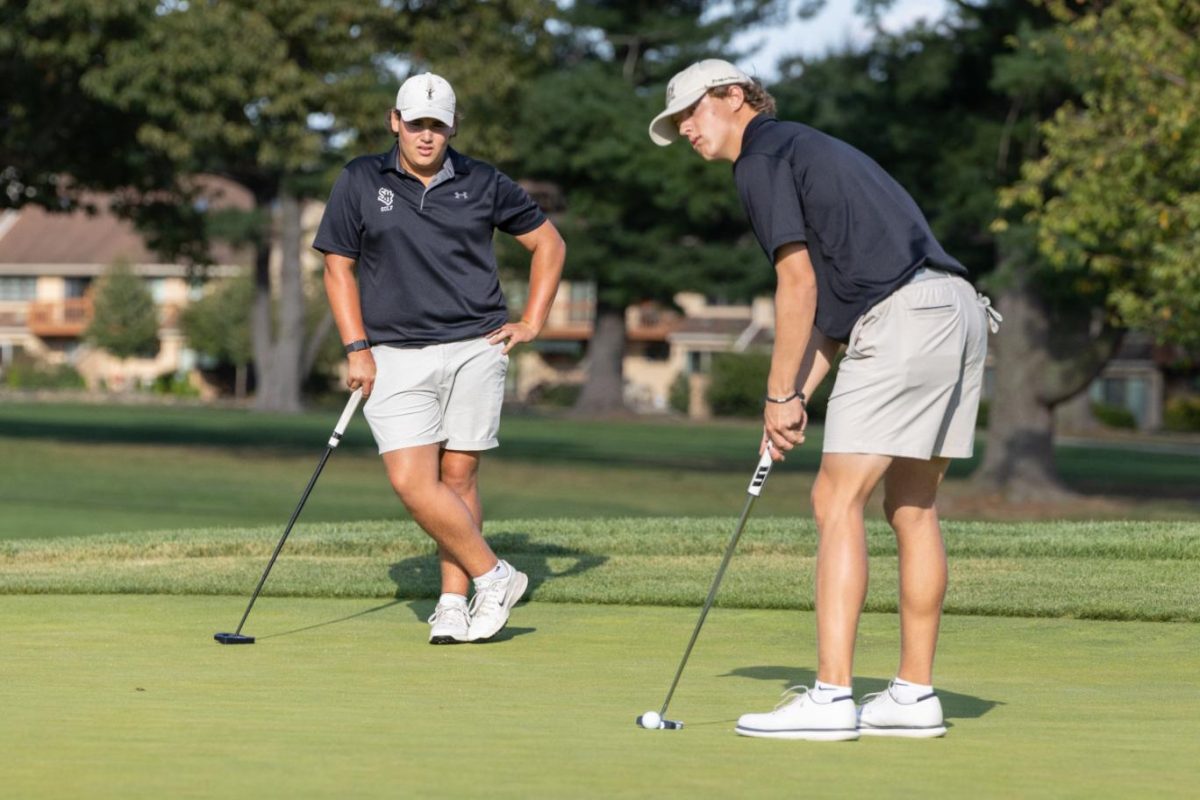 Eddie Gebhardt (12) putts while Luca Kleinschmidt (12) looks on during at the last hole of the golf team's match against Harriton on Wednesday, August 27 at Springhaven Country Club. Gebhardt said the team has been working on staying consistent, steady and level while playing. "If you stay calm and you treat each shot the same, no matter what it's for, you play better," he said.