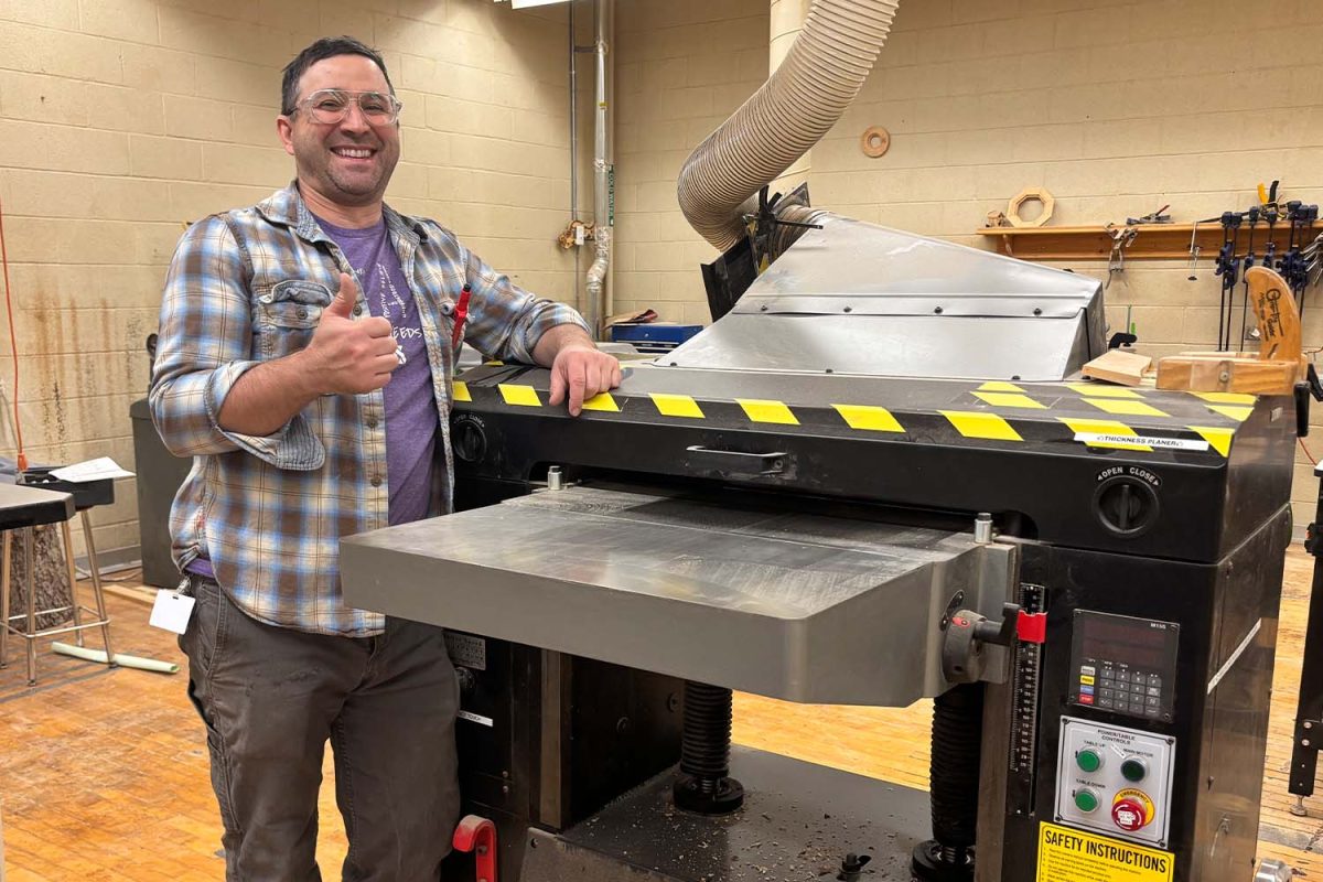 Wood tech teacher Mr. Brett Thomas leans over the wood planer in the classroom on September 20 during fifth block.