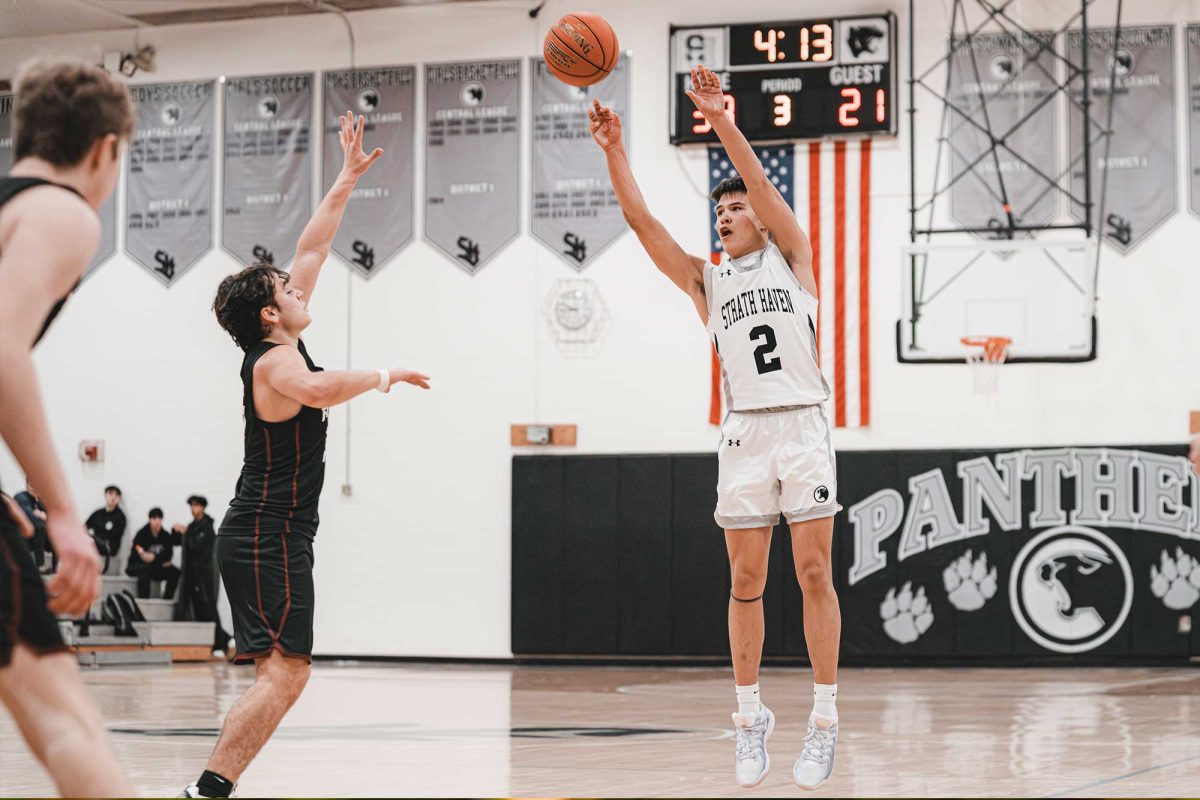 Theo Jauregui (12) shoots the ball over a Radnor defender during the 2024-25 season. The game clock in the background doesn’t have a shot clock. 