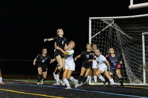 Ava Hurwitz (11) jumps into the air in an attempt to hit a header into the goal as the ball comes towards her during a game against Ridley on September 30. Hurwitz scored two goals during the game. 