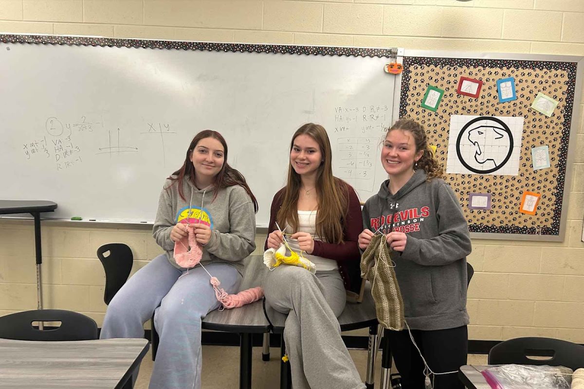 Maisie Sentivan, (11) Abby Bachar, (12) and Eryn Broome (12) pose with knitting and crocheting projects in Ms. Winkowski's room during fifth block.