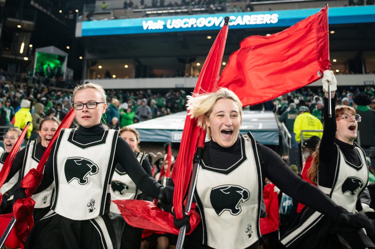 Silks members Isabel Dourte (10) and Levi Ouellette (12) rush the field to perform the halftime show at the Lincoln Financial Field on November 16. The marching band was invited to perform during halftime for six minutes.