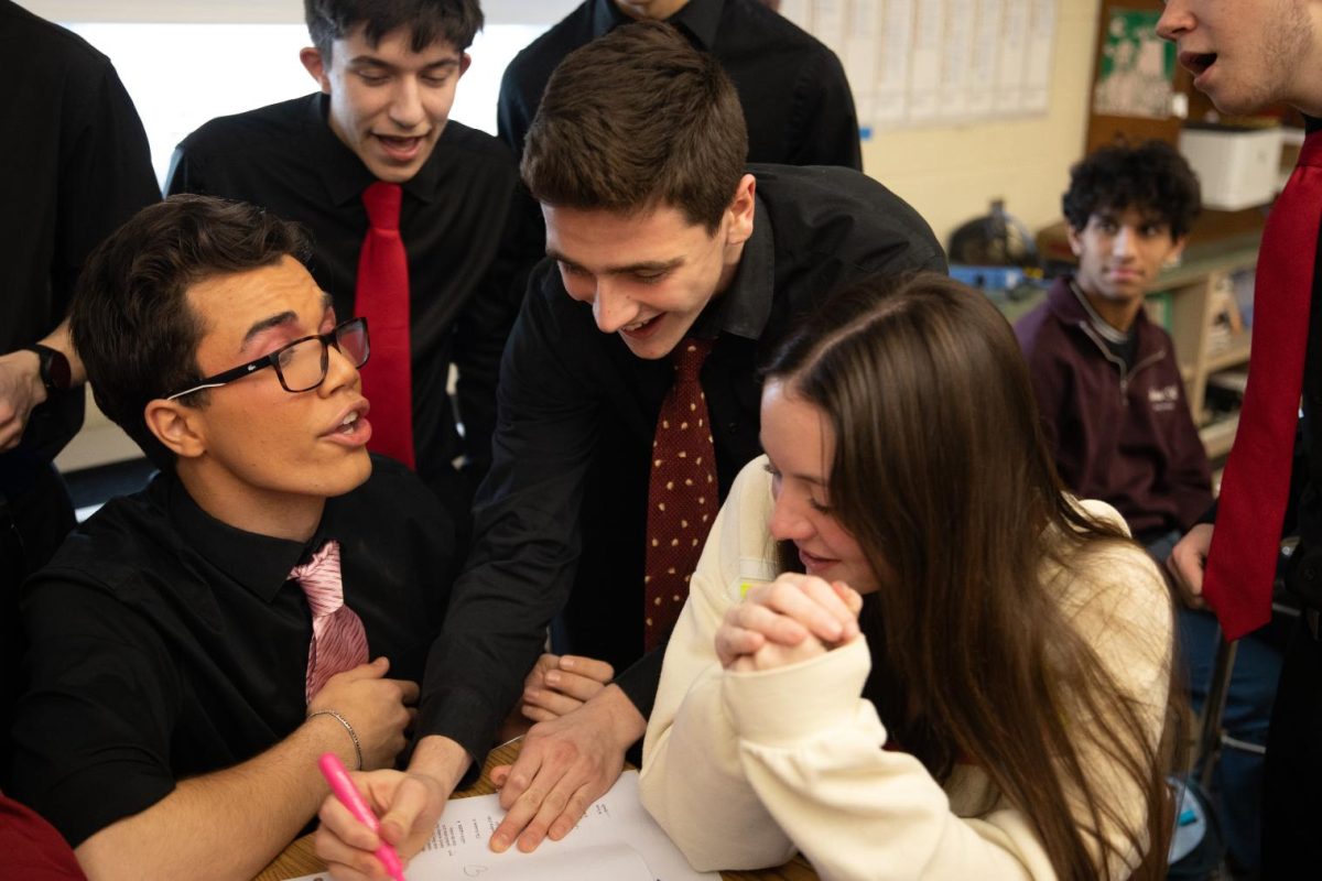 Gordon Morris (12) sings to Anna Bronchetti (12) as Jack Logue (12) draws hearts on her paper during classes on February 12. The Silvertones often drew hearts on students' papers or googled pictures of hearts on their Chromebooks when singing to students.