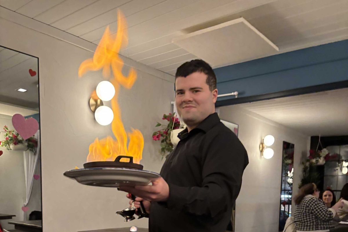 A waiter serves the saganaki dish with an elaborate show of lighting it on fire.