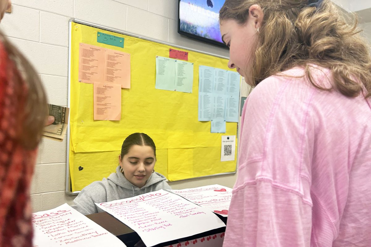 Elizabeth Whitehead (10) purchases a singing valentine from Silvertones member Asha Miller (10). Silvertones members take turns selling valentines to interested students during lunches.