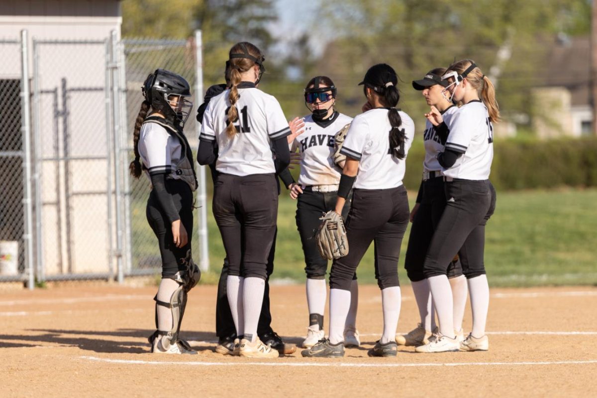 Members of varsity softball team huddle up during time out to discuss next moves in the field.