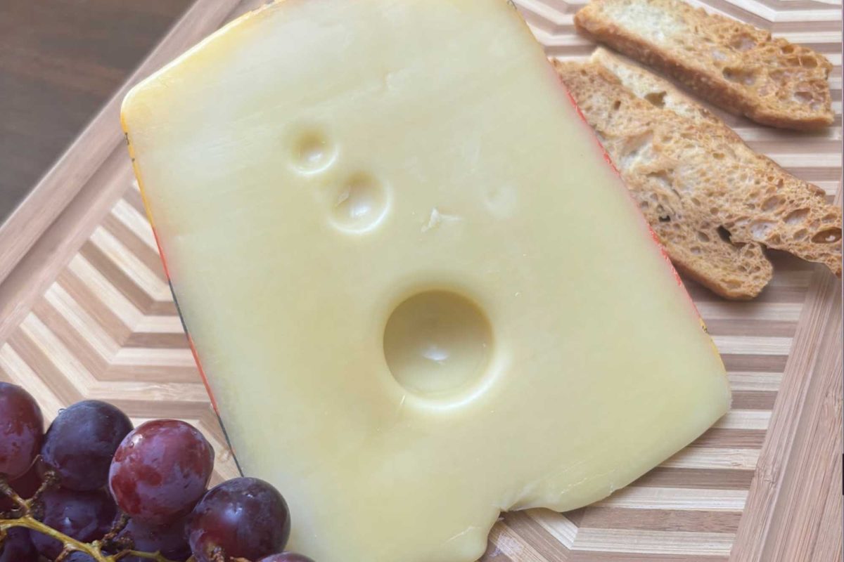 Jarlsberg cheese being served alongside bread and grapes.