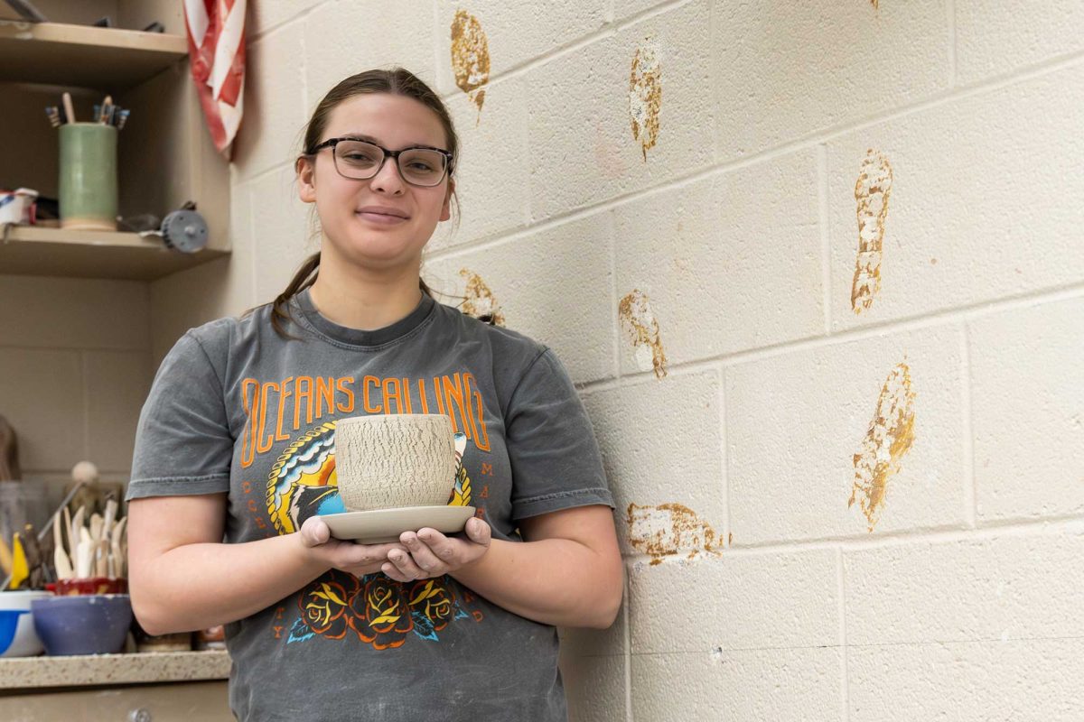 Amelia Badura (12) poses with a greenware pot in the ceramics studio.